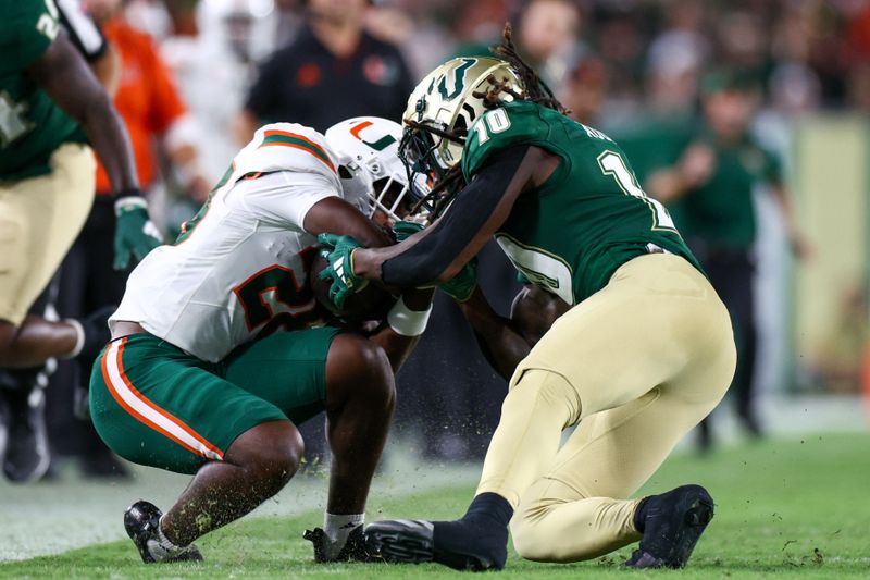Sep 21, 2024; Tampa, Florida, USA; Miami Hurricanes running back Ajay Allen (28) is tackled by South Florida Bulls safety D'Marco Augustin (10) in the third quarter at Raymond James Stadium. Mandatory Credit: Nathan Ray Seebeck-Imagn Images