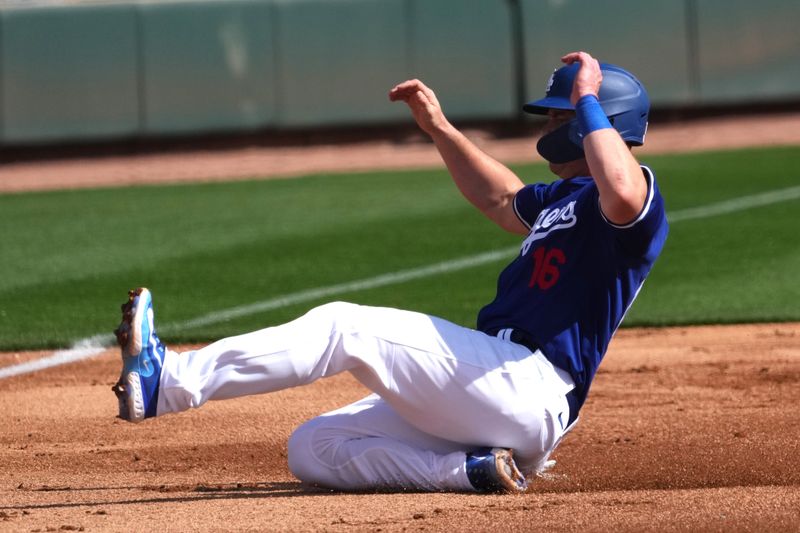 Feb 25, 2024; Phoenix, Arizona, USA; Los Angeles Dodgers catcher Will Smith (16) slides into third base against the Oakland Athletics during the first inning at Camelback Ranch-Glendale. Mandatory Credit: Joe Camporeale-USA TODAY Sports