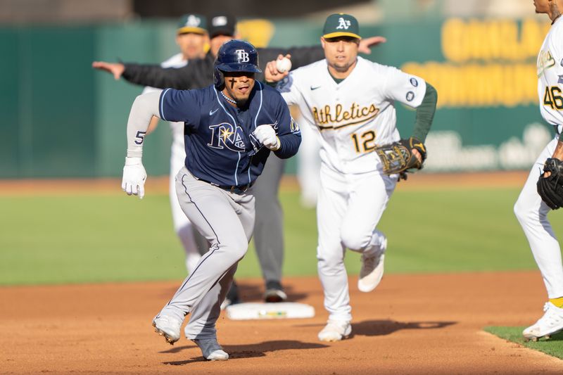 Jun 14, 2023; Oakland, California, USA;  Oakland Athletics third baseman Aledmys Diaz (12) attempts to chase down Tampa Bay Rays shortstop Wander Franco (5) during the first inning at Oakland-Alameda County Coliseum. Mandatory Credit: Stan Szeto-USA TODAY Sports