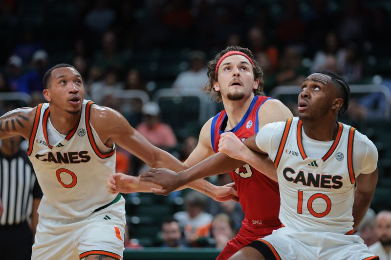 Jan 18, 2025; Coral Gables, Florida, USA; Southern Methodist Mustangs forward Matt Cross (33) looks for a rebound against Miami Hurricanes guard Paul Djobet (10) and guard Matthew Cleveland (0) during the second half at Watsco Center. Mandatory Credit: Sam Navarro-Imagn Images