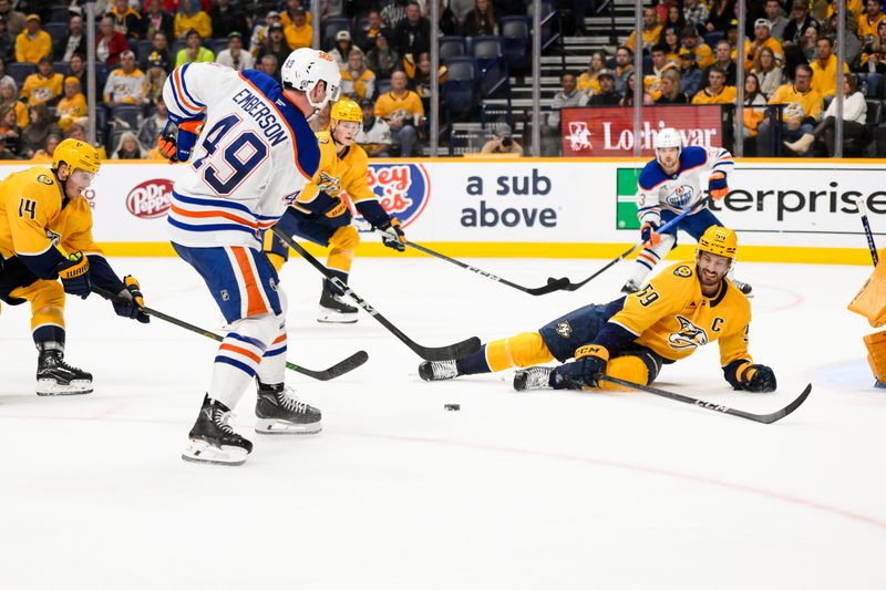 Oct 31, 2024; Nashville, Tennessee, USA;  Edmonton Oilers defenseman Ty Emberson (49) takes a shot on goal as Nashville Predators center Ryan O'Reilly (90) defends during the second period at Bridgestone Arena. Mandatory Credit: Steve Roberts-Imagn Images