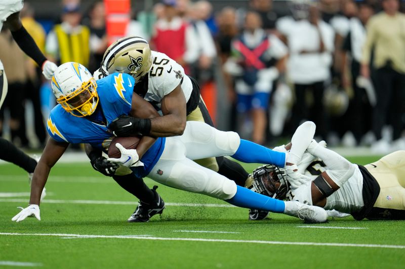 Los Angeles Chargers running back Isaiah Spiller is tackled by New Orleans Saints defensive end Isaiah Foskey (55) and safety Jordan Howden in the first half of an NFL football game in Inglewood, Calif., Sunday, Aug. 20, 2023. (AP Photo/Marcio Jose Sanchez)