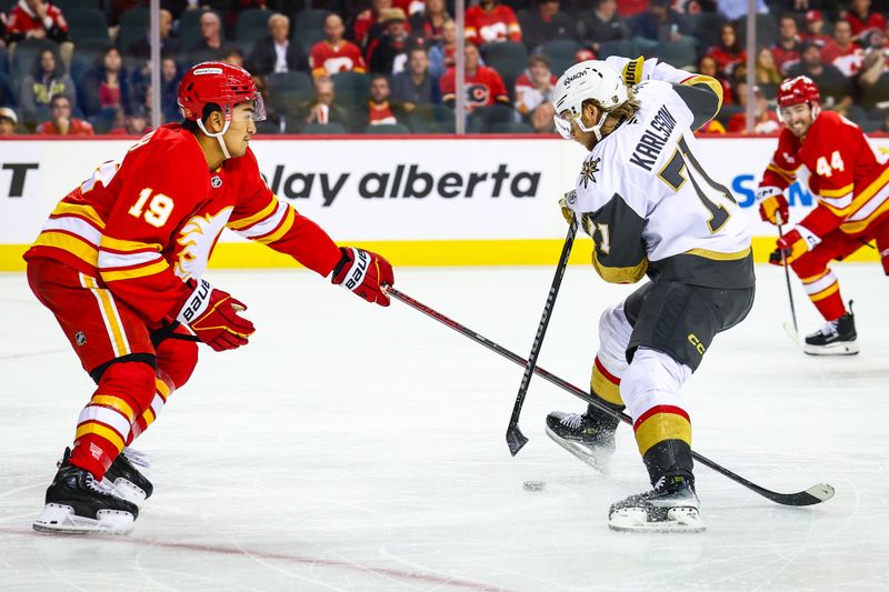 Oct 14, 2025; Calgary, Alberta, CAN; Vegas Golden Knights center William Karlsson (71) and Calgary Flames defenseman Zayne Parekh (19) battles for the puck during the third period at Scotiabank Saddledome. Mandatory Credit: Sergei Belski-Imagn Images