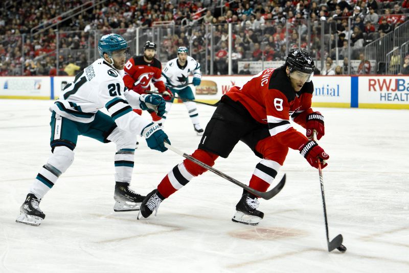 Nov 10, 2024; Newark, New Jersey, USA; New Jersey Devils defenseman Johnathan Kovacevic (8) skates with the puck against San Jose Sharks center Alexander Wennberg (21) during the third period at Prudential Center. Mandatory Credit: John Jones-Imagn Images