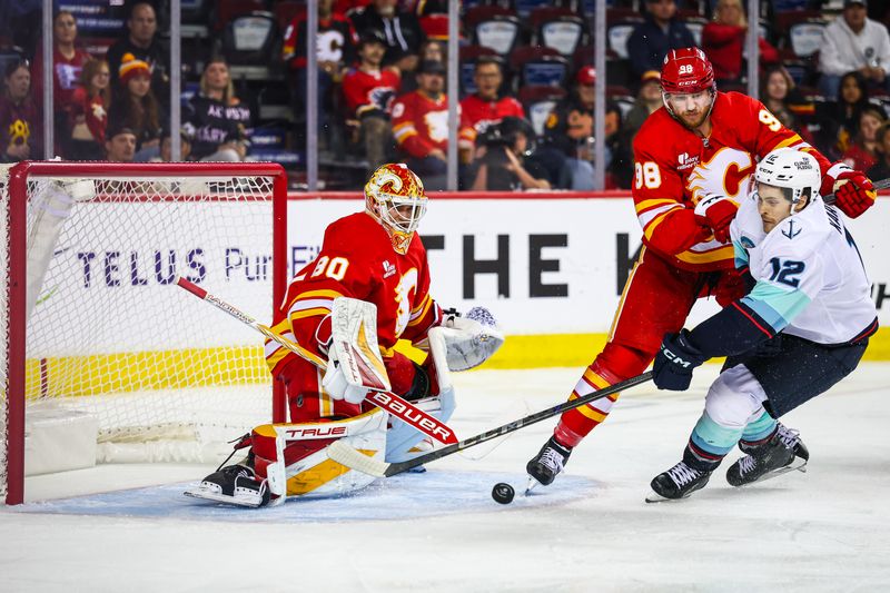 Sep 23, 2025; Calgary, Alberta, CAN; Calgary Flames defenseman Ilya Solovyov (98) and Seattle Kraken left wing Tye Kartye (12) battles for the puck in front of Calgary Flames goaltender Owen Say (80) during the third period at Scotiabank Saddledome. Mandatory Credit: Sergei Belski-Imagn Images