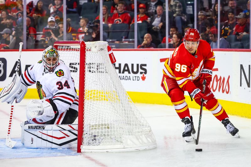 Oct 15, 2024; Calgary, Alberta, CAN; Calgary Flames left wing Andrei Kuzmenko (96) controls the puck behind the net of Chicago Blackhawks goaltender Petr Mrazek (34) during the third period at Scotiabank Saddledome. Mandatory Credit: Sergei Belski-Imagn Images