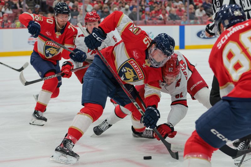 Nov 30, 2024; Sunrise, Florida, USA; Florida Panthers center Anton Lundell (15) and Carolina Hurricanes center Jesperi Kotkaniemi (82) face-off during the first period at Amerant Bank Arena. Mandatory Credit: Sam Navarro-Imagn Images