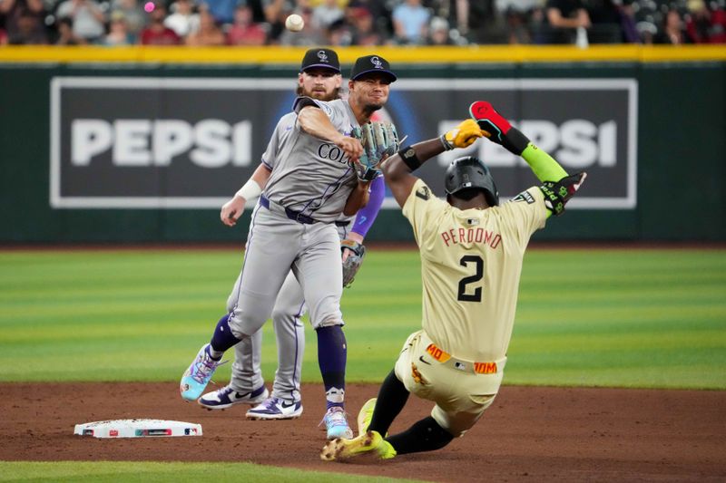 Aug 13, 2024; Phoenix, Arizona, USA; Colorado Rockies shortstop Ezequiel Tovar (14) throws to first base for a double play after forcing out Arizona Diamondbacks shortstop Geraldo Perdomo (2) at second during the seventh inning at Chase Field. Mandatory Credit: Joe Camporeale-USA TODAY Sports