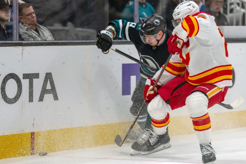 Dec 16, 2025; San Jose, California, USA; Calgary Flames right wing Matt Coronato (27) and San Jose Sharks defenseman Dmitry Orlov (9) battle for the puck during the first period at SAP Center at San Jose. Mandatory Credit: Neville E. Guard-Imagn Images
