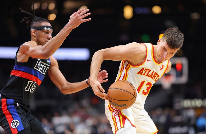 ATLANTA, GEORGIA - APRIL 03:  Bogdan Bogdanovic #13 of the Atlanta Hawks nearly loses the ball as he dribbles it behind his back into the hands of Tosan Evbuomwan #18 of the Detroit Pistons during the second quarter at State Farm Arena on April 03, 2024 in Atlanta, Georgia.  NOTE TO USER: User expressly acknowledges and agrees that, by downloading and/or using this photograph, user is consenting to the terms and conditions of the Getty Images License Agreement.  (Photo by Kevin C. Cox/Getty Images)