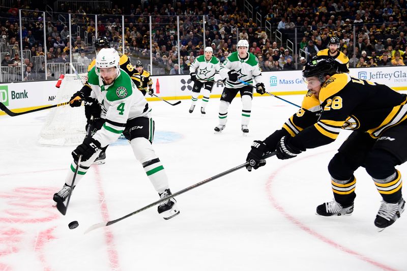 Oct 24, 2024; Boston, Massachusetts, USA;  Dallas Stars defenseman Miro Heiskanen (4) and Boston Bruins center Elias Lindholm (28) battle for the puck during the first period at TD Garden. Mandatory Credit: Bob DeChiara-Imagn Images