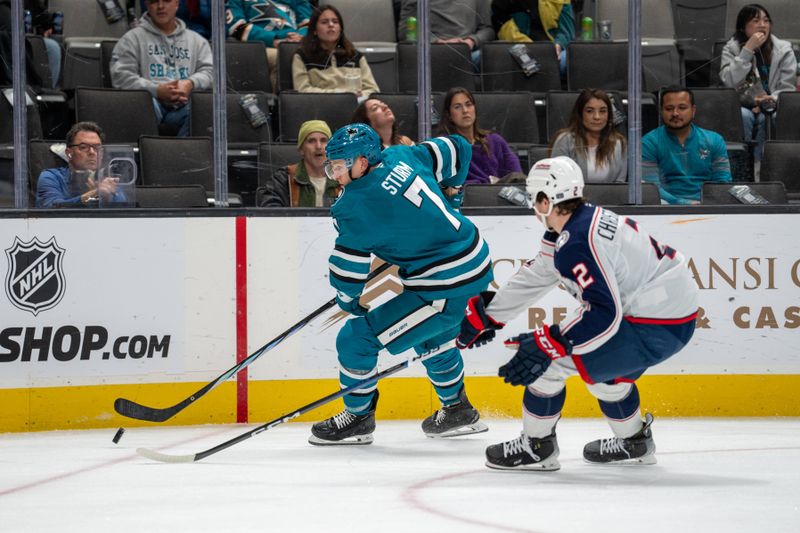 Nov 5, 2024; San Jose, California, USA;  San Jose Sharks center Nico Sturm (7) controls the puck against Columbus Blue Jackets defenseman Jake Christiansen (2) during the second period at SAP Center at San Jose. Mandatory Credit: Neville E. Guard-Imagn Images