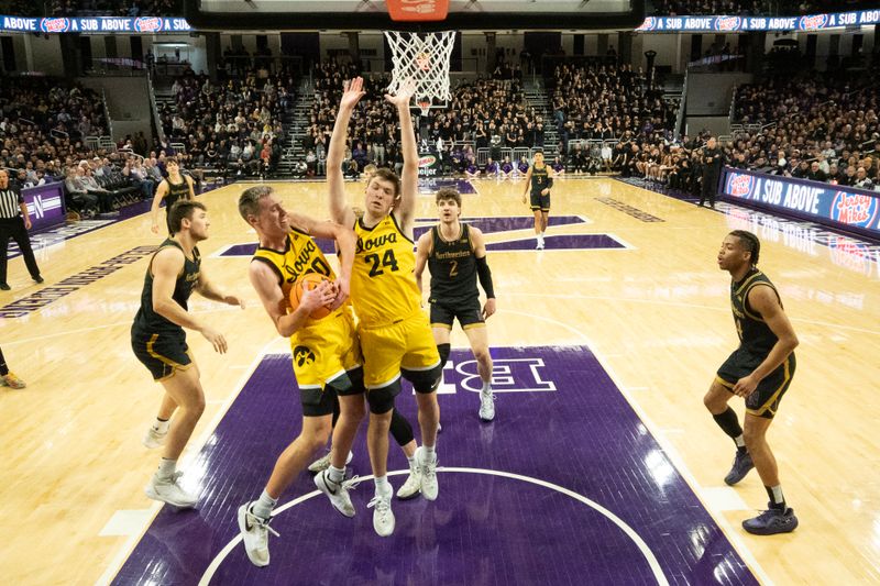 Feb 28, 2025; Evanston, Illinois, USA; Iowa Hawkeyes forward Payton Sandfort (20) and forward Pryce Sandfort (24) grab a rebound against the Northwestern Wildcats during the second half at Welsh-Ryan Arena. Mandatory Credit: David Banks-Imagn Images