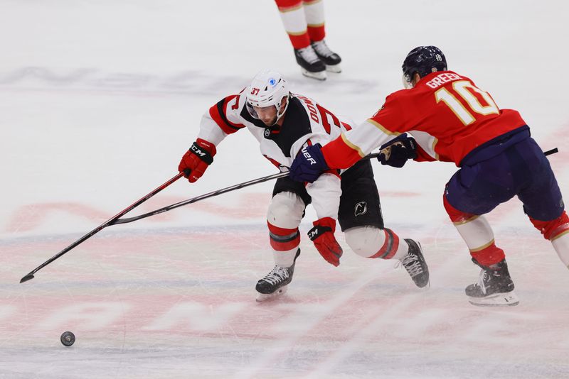 Nov 14, 2024; Sunrise, Florida, USA; New Jersey Devils center Justin Dowling (37) moves the puck past Florida Panthers left wing A.J. Greer (10) during the third period at Amerant Bank Arena. Mandatory Credit: Sam Navarro-Imagn Images