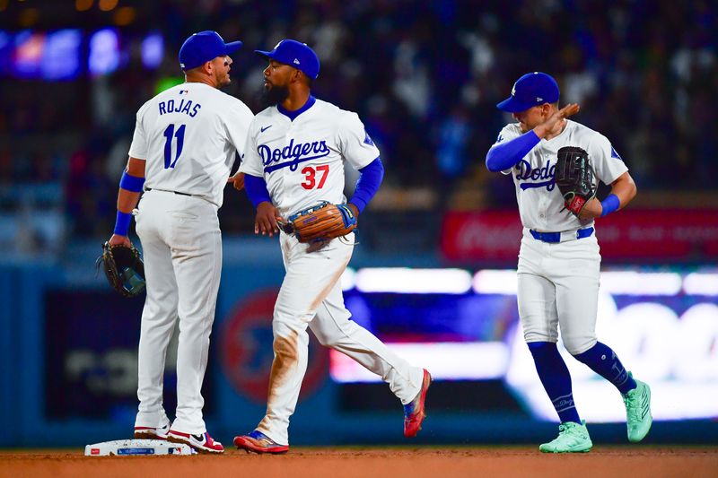 Apr 3, 2024; Los Angeles, California, USA; Los Angeles Dodgers shortstop Miguel Rojas (11) right fielder Teoscar Hernandez (37) and center fielder Enrique Hernandez (8) celebrate the victory against the San Francisco Giants at Dodger Stadium. Mandatory Credit: Gary A. Vasquez-USA TODAY Sports