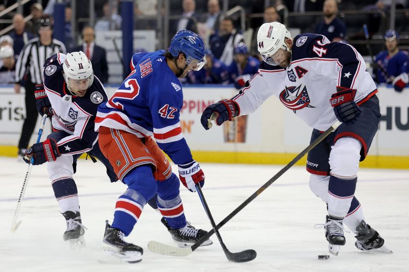 Mar 2, 2026; New York, New York, USA; New York Rangers center Noah Laba (42) fights for the puck against Columbus Blue Jackets left wing Miles Wood (11) and defenseman Erik Gudbranson (44) during the second period at Madison Square Garden. Mandatory Credit: Brad Penner-Imagn Images