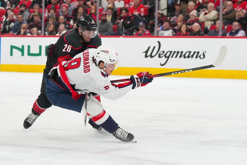 Nov 11, 2025; Raleigh, North Carolina, USA; Washington Capitals right wing Ryan Leonard (9) shoots the puck defended by Carolina Hurricanes defenseman Sean Walker (26) during the second period at Lenovo Center. Mandatory Credit: James Guillory-Imagn Images