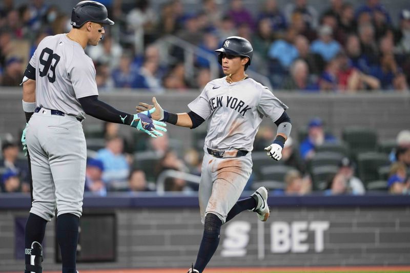 Apr 17, 2024; Toronto, Ontario, CAN; New York Yankees third base Oswaldo Cabrera (95) scores a run and celebrates with center fielder Aaron Judge (99) against the Toronto Blue Jays during the fifth inning at Rogers Centre. Mandatory Credit: Nick Turchiaro-USA TODAY Sports