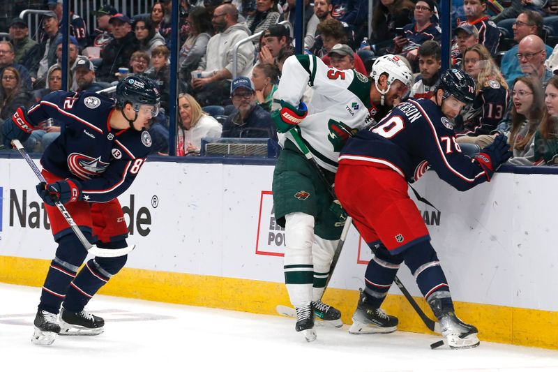 Oct 19, 2024; Columbus, Ohio, USA; Minnesota Wild defenseman Jacob Middleton (5) and Columbus Blue Jackets defenseman Damon Severson (78) battle for a puck during the second period  at Nationwide Arena. Mandatory Credit: Russell LaBounty-Imagn Images