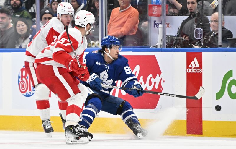 Jan 14, 2024; Toronto, Ontario, CAN;  Toronto Maple Leafs forward Nick Robertson (89) plays the puck away from Detroit Red Wings forwards David Perron (57) and Lucas Raymond (23) in the third period at Scotiabank Arena. Mandatory Credit: Dan Hamilton-USA TODAY Sports