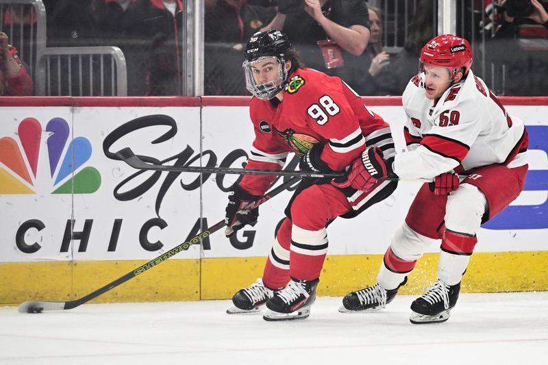 Apr 14, 2024; Chicago, Illinois, USA; Chicago Blackhawks forward Connor Bedard (98) controls the puck while being pursued by Carolina Hurricanes forward Jake Guentzel (59) in the first period at United Center. Mandatory Credit: Jamie Sabau-USA TODAY Sports