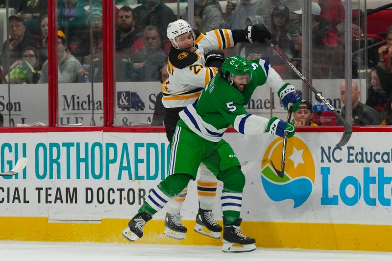 Mar 26, 2023; Raleigh, North Carolina, USA;  Carolina Hurricanes defenseman Jalen Chatfield (5) checks Boston Bruins right wing Garnet Hathaway (21) during the second period at PNC Arena. Mandatory Credit: James Guillory-USA TODAY Sports