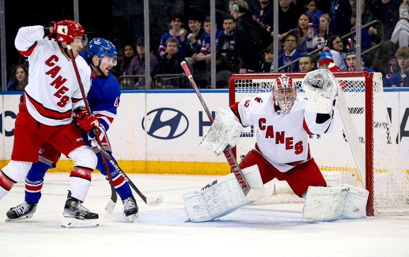 Jan 2, 2024; New York, New York, USA; Carolina Hurricanes goalie Pyotr Kochetkov (52) makes a glove save while New York Rangers forward Alexis Lafreniere (13) and Carolina Hurricanes defenseman Dmitry Orlov (7) battle in front during the first period at Madison Square Garden. Mandatory Credit: Danny Wild-USA TODAY Sports