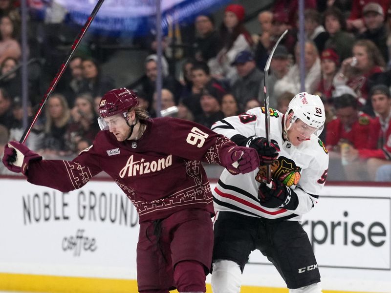 Mar 18, 2023; Tempe, Arizona, USA; Arizona Coyotes defenseman J.J. Moser (90) and Chicago Blackhawks right wing Buddy Robinson (53) battle for the puck during the third period at Mullett Arena. Mandatory Credit: Joe Camporeale-USA TODAY Sports