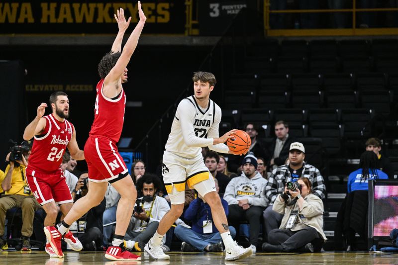 Jan 7, 2025; Iowa City, Iowa, USA; Iowa Hawkeyes forward Owen Freeman (32) controls the ball as Nebraska Cornhuskers center Braxton Meah (34) and guard Rollie Worster (24) defend during the first half at Carver-Hawkeye Arena. Mandatory Credit: Jeffrey Becker-Imagn Images