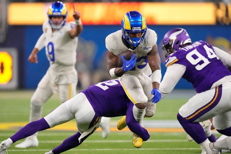 Los Angeles Rams running back Kyren Williams, center top, runs for a first down as Minnesota Vikings cornerback Stephon Gilmore (2) and defensive tackle Taki Taimani (94) try to tackle him during the second half of an NFL football game, Thursday, Oct. 24, 2024, in Inglewood, Calif. (AP Photo/Mark J. Terrill)