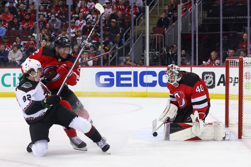 Oct 13, 2023; Newark, New Jersey, USA; New Jersey Devils goaltender Akira Schmid (40) makes a save on Arizona Coyotes center Logan Cooley (92) during the first period at Prudential Center. Mandatory Credit: Ed Mulholland-USA TODAY Sports