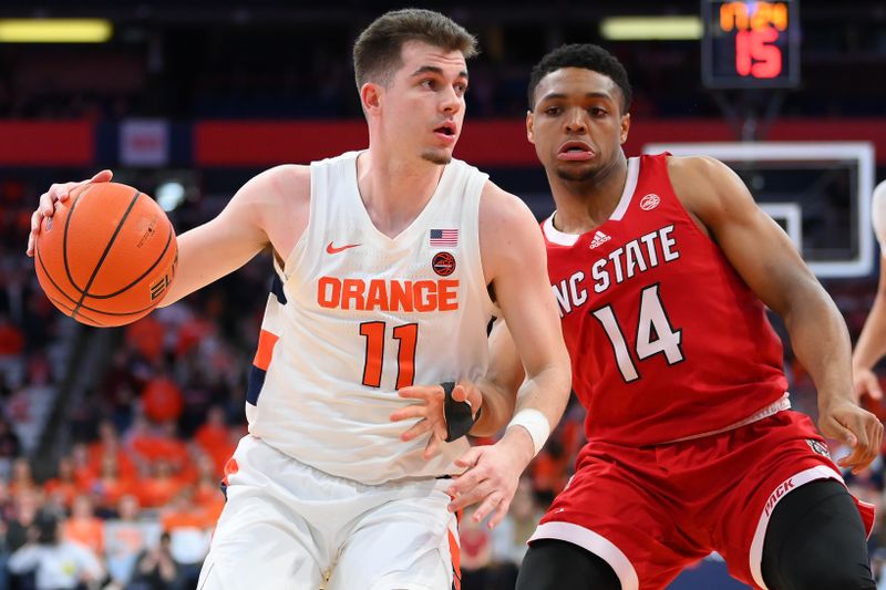 Feb 14, 2023; Syracuse, New York, USA; Syracuse Orange guard Joseph Girard III (11) drives to the basket as North Carolina State Wolfpack guard Casey Morsell (14) defends during the first half at the JMA Wireless Dome. Mandatory Credit: Rich Barnes-USA TODAY Sports