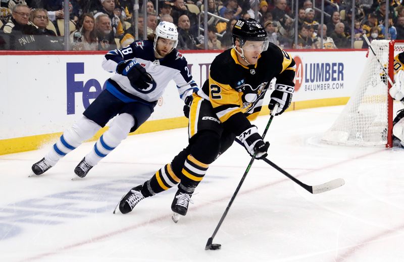 Jan 13, 2023; Pittsburgh, Pennsylvania, USA; Pittsburgh Penguins defenseman Chad Ruhwedel (2) skates with the puck ahead of Winnipeg Jets center Kevin Stenlund (28) during the first period at PPG Paints Arena. Mandatory Credit: Charles LeClaire-USA TODAY Sports