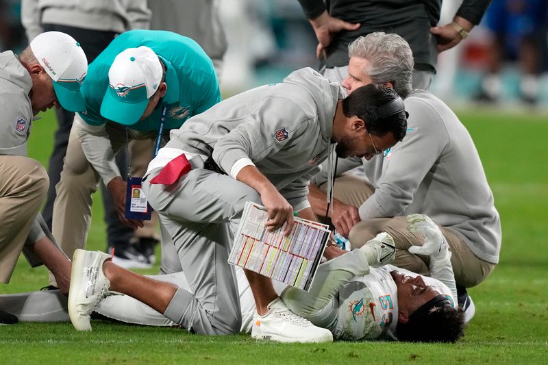 Miami Dolphins head coach Mike McDaniel is on the field with injured linebacker Cameron Goode (53) during the second half of an NFL football game against the Buffalo Bills, Sunday, Jan. 7, 2024, in Miami Gardens, Fla. (AP Photo/Lynne Sladky)