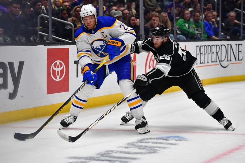 Feb 13, 2023; Los Angeles, California, USA; Buffalo Sabres right wing Kyle Okposo (21) moves the puck ahead of Los Angeles Kings defenseman Sean Walker (26) during the third period at Crypto.com Arena. Mandatory Credit: Gary A. Vasquez-USA TODAY Sports