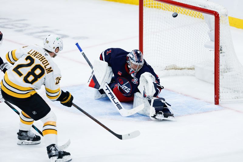 Dec 11, 2025; Winnipeg, Manitoba, CAN; Boston Bruins forward Elias Lindholm (28) scores on Winnipeg Jets goalie Eric Comrie (1) during the third period at Canada Life Centre.  Mandatory Credit: Terrence Lee-Imagn Images