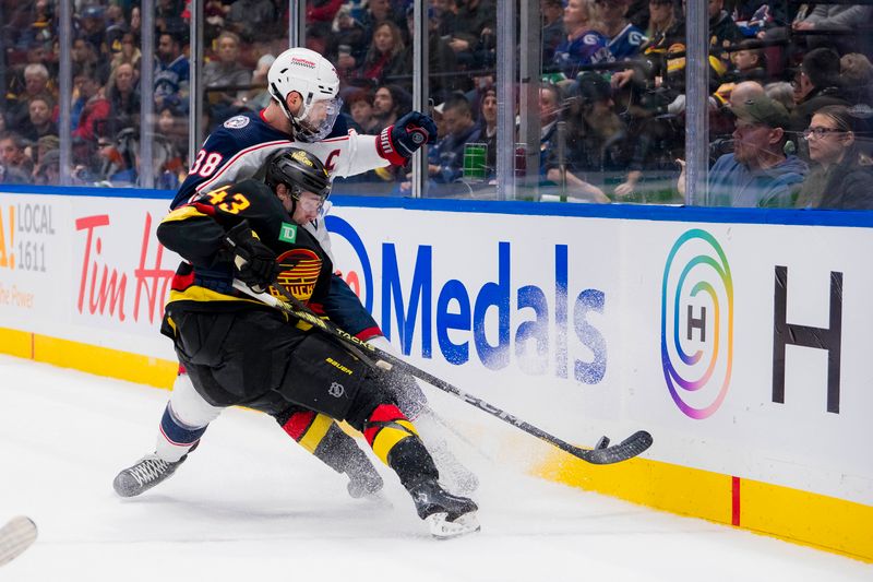 Jan 27, 2024; Vancouver, British Columbia, CAN; Columbus Blue Jackets forward Boone Jenner (38) checks Vancouver Canucks defenseman Quinn Hughes (43) in the first period at Rogers Arena. Mandatory Credit: Bob Frid-USA TODAY Sports