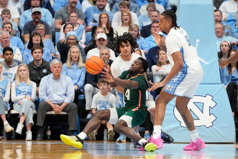 Feb 26, 2024; Chapel Hill, North Carolina, USA; Miami (Fl) Hurricanes guard Bensley Joseph (4) slips as North Carolina Tar Heels guard Elliot Cadeau (2) and forward Armando Bacot (5) defend in the second half at Dean E. Smith Center. Mandatory Credit: Bob Donnan-USA TODAY Sports