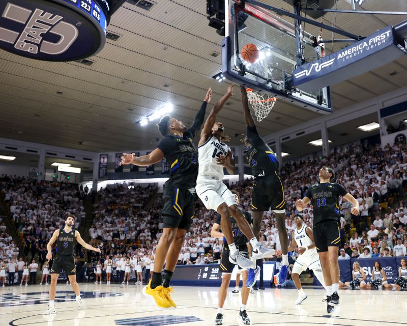 Jan 30, 2024; Logan, Utah, USA; Utah State Aggies guard Josh Uduje (14) lays the ball up San Jose State Spartans guard Myron Amey Jr. (left) and center Adrame Diongue (4) during the second half at Dee Glen Smith Spectrum. Mandatory Credit: Rob Gray-USA TODAY Sports