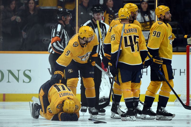 Dec 27, 2023; Nashville, Tennessee, USA; Nashville Predators center Gustav Nyquist (14) is checked on by left wing Filip Forsberg (9) after scoring and colliding with a Carolina Hurricanes player during the second period at Bridgestone Arena. Mandatory Credit: Christopher Hanewinckel-USA TODAY Sports