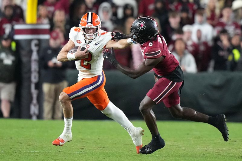 Nov 25, 2023; Columbia, South Carolina, USA; Clemson Tigers quarterback Cade Klubnik (2) gives a stiff arm to South Carolina Gamecocks defensive back Marcellas Dial (6) in the second half at Williams-Brice Stadium. Mandatory Credit: David Yeazell-USA TODAY Sports