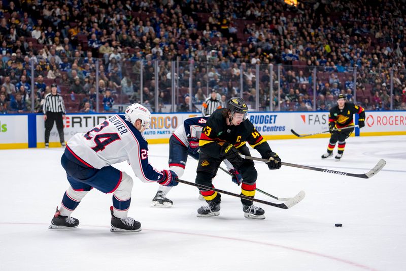 Dec 6, 2024; Vancouver, British Columbia, CAN; Columbus Blue Jackets forward Mathieu Olivier (24) stick checks Vancouver Canucks defenseman Quinn Hughes (43) during the second period at Rogers Arena. Mandatory Credit: Bob Frid-Imagn Images