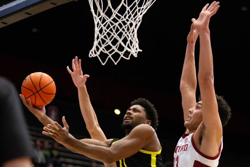 Feb 22, 2024; Stanford, California, USA; Oregon Ducks guard Kario Oquendo (0) lays the ball up ahead of Stanford Cardinal forward Brandon Angel (23) during the first half at Maples Pavilion. Mandatory Credit: D. Ross Cameron-USA TODAY Sports