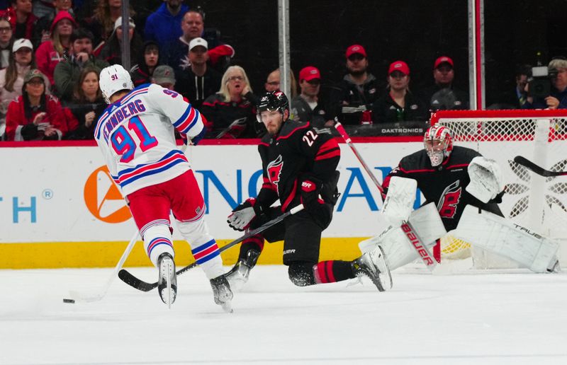 Mar 12, 2024; Raleigh, North Carolina, USA; Carolina Hurricanes defenseman Brett Pesce (22) goes out to block the shot by New York Rangers center Alex Wennberg (91) during the first period at PNC Arena. Mandatory Credit: James Guillory-USA TODAY Sports