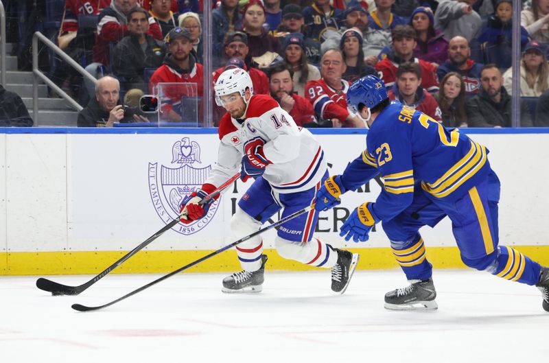 Jan 31, 2026; Buffalo, New York, USA;  Montréal Canadiens center Nick Suzuki (14) carries the puck as Buffalo Sabres defenseman Mattias Samuelsson (23) defends during the first period at KeyBank Center. Mandatory Credit: Timothy T. Ludwig-Imagn Images