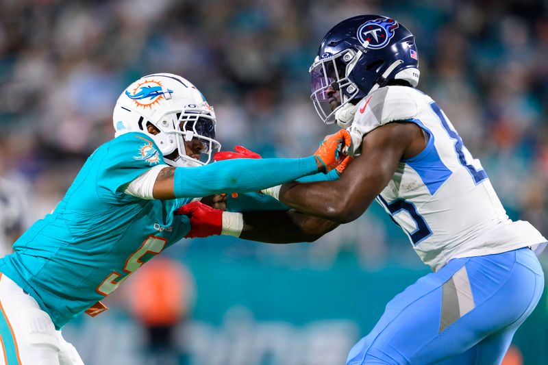 Tennessee Titans tight end Chig Okonkwo (85) holds Miami Dolphins cornerback Jalen Ramsey (5) during an NFL football game Monday, Dec. 12, 2023, in Miami Gardens, Fla. (AP Photo/Doug Murray)