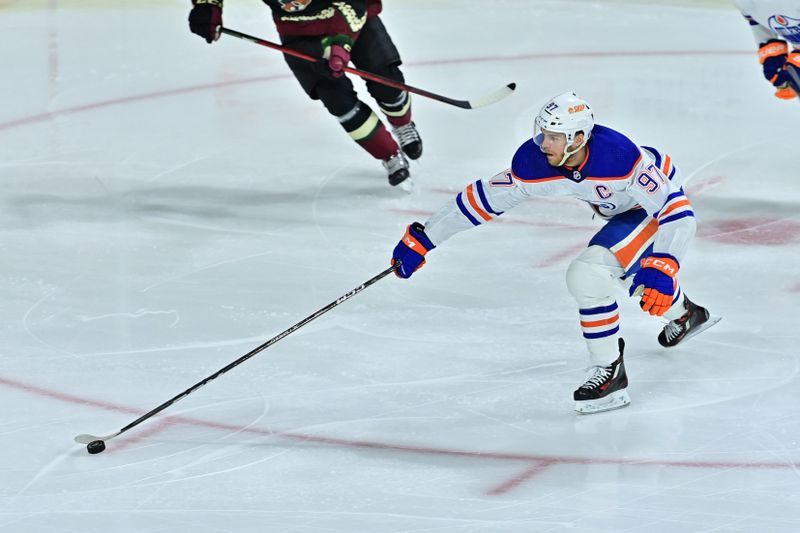 Mar 27, 2023; Tempe, Arizona, USA;  Edmonton Oilers center Connor McDavid (97) reachs for the puck in the first period against the Arizona Coyotes at Mullett Arena. Mandatory Credit: Matt Kartozian-USA TODAY Sports