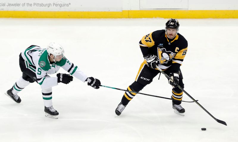 Dec 12, 2022; Pittsburgh, Pennsylvania, USA; Pittsburgh Penguins center Sidney Crosby (87) moves the puck as Dallas Stars defenseman Nils Lundkvist (5) defends during the second period at PPG Paints Arena. Mandatory Credit: Charles LeClaire-USA TODAY Sports