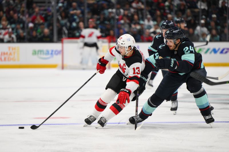 Jan 6, 2025; Seattle, Washington, USA; New Jersey Devils center Nico Hischier (13) plays the puck while defended by Seattle Kraken defenseman Jamie Oleksiak (24) during the second period at Climate Pledge Arena. Mandatory Credit: Steven Bisig-Imagn Images