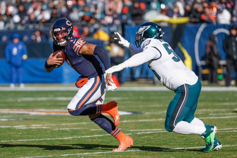 Chicago Bears quarterback Justin Fields (1) rushes with the ball against Philadelphia Eagles defensive end Brandon Graham (55) during the first half of an NFL football game, Sunday, Dec. 18, 2022, in Chicago. (AP Photo/Kamil Krzaczynski)